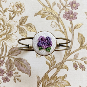 Bracciale artigianale Fildisogno con simbolo ricamato, lavorazione dettagliata e stile unico, visibile in primo piano.