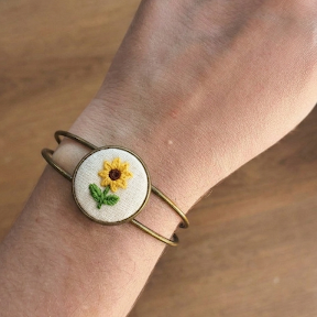 Bracciale artigianale Fildisogno con simbolo ricamato, in tessuto colorato e dettagli fatti a mano.