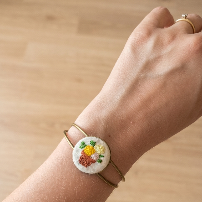 Bracciale artigianale Fildisogno con simbolo ricamato, dettaglio di tessitura e cuciture su pelle naturale.