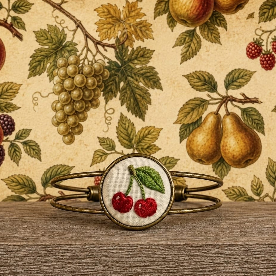 Bracciale artigianale Fildisogno con simbolo ricamato in tessuto colorato e dettagli lavorati a mano.