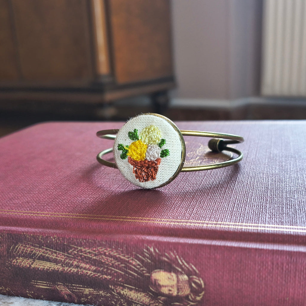 Bracciale artigianale Fildisogno con simbolo ricamato, dettagli raffinati e lavorazione artigianale in primo piano.
