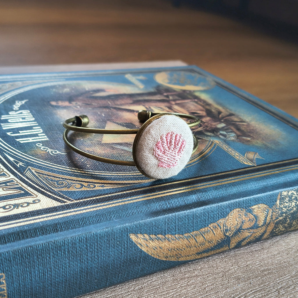 Bracciale artigianale Fildisogno con simbolo ricamato, dettaglio di design unico e lavorazione a mano.
