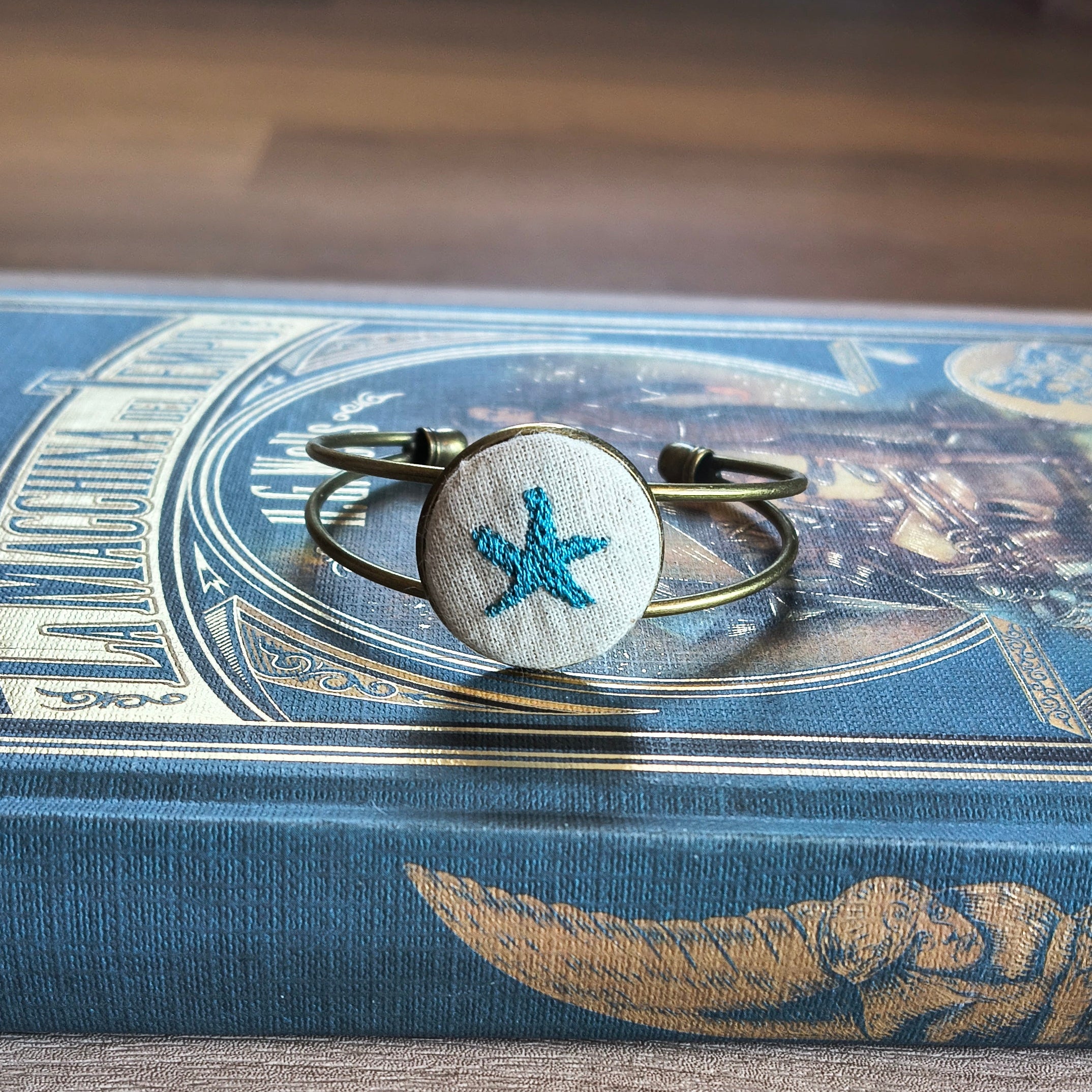 Bracciale artigianale Fildisogno con simbolo ricamato, dettagli raffinati e lavorazione manuale visibili nell'immagine.