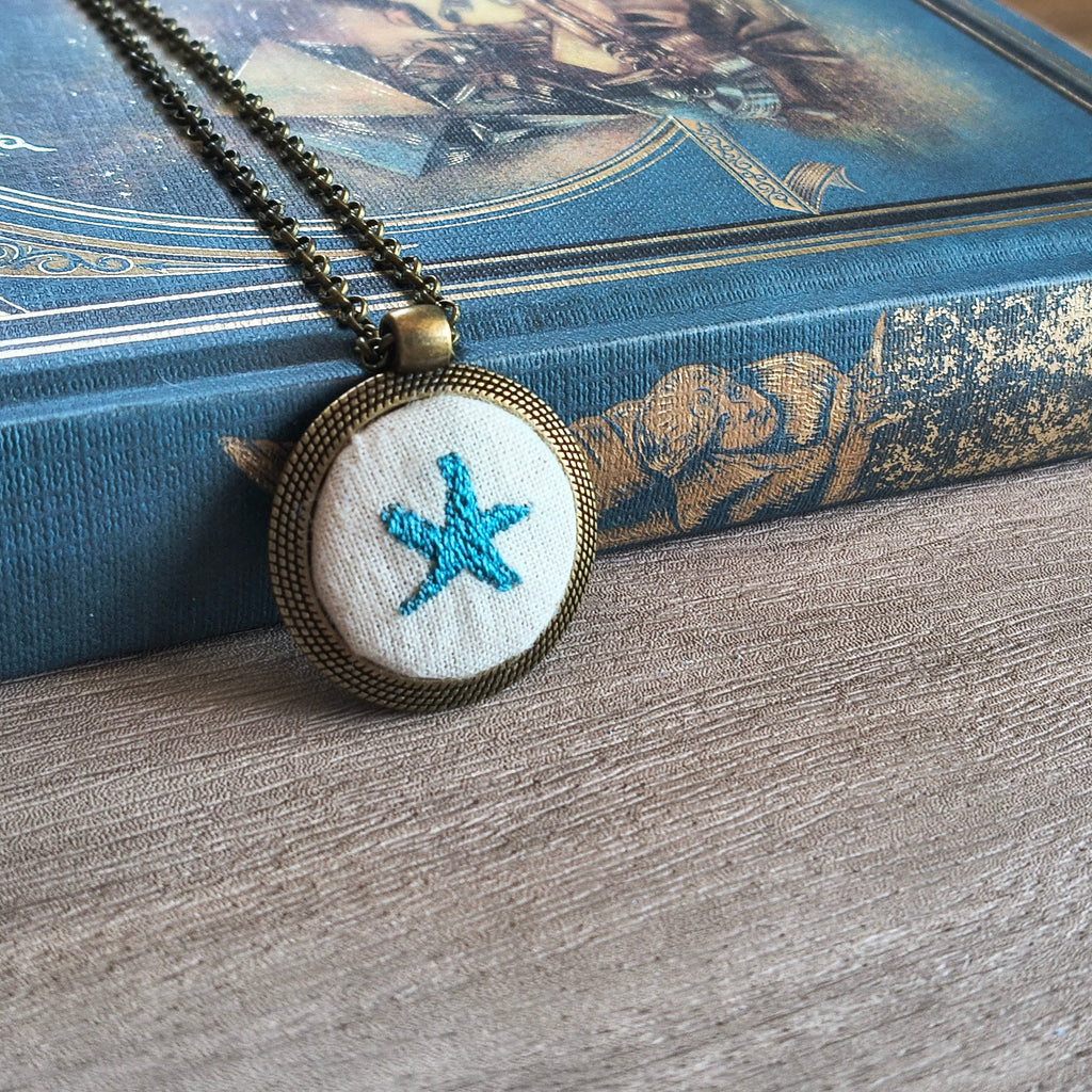 Collana artigianale Fildisogno con simbolo ricamato, dettagli raffinati e lavorazione artigianale, visibile nell'immagine.