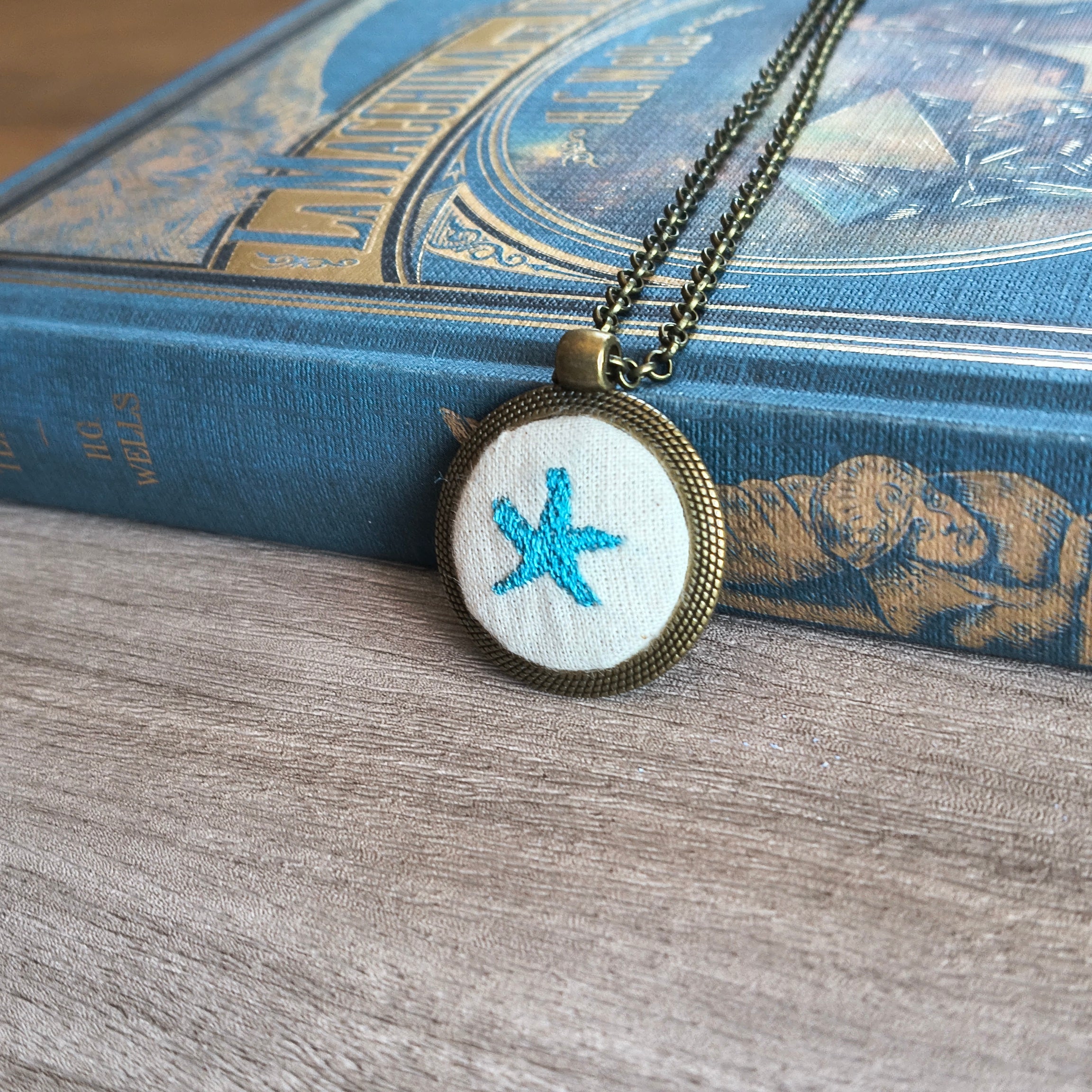Collana artigianale con simbolo ricamato, realizzata da Fildisogno, visibile con dettaglio di ricamo e design unico.