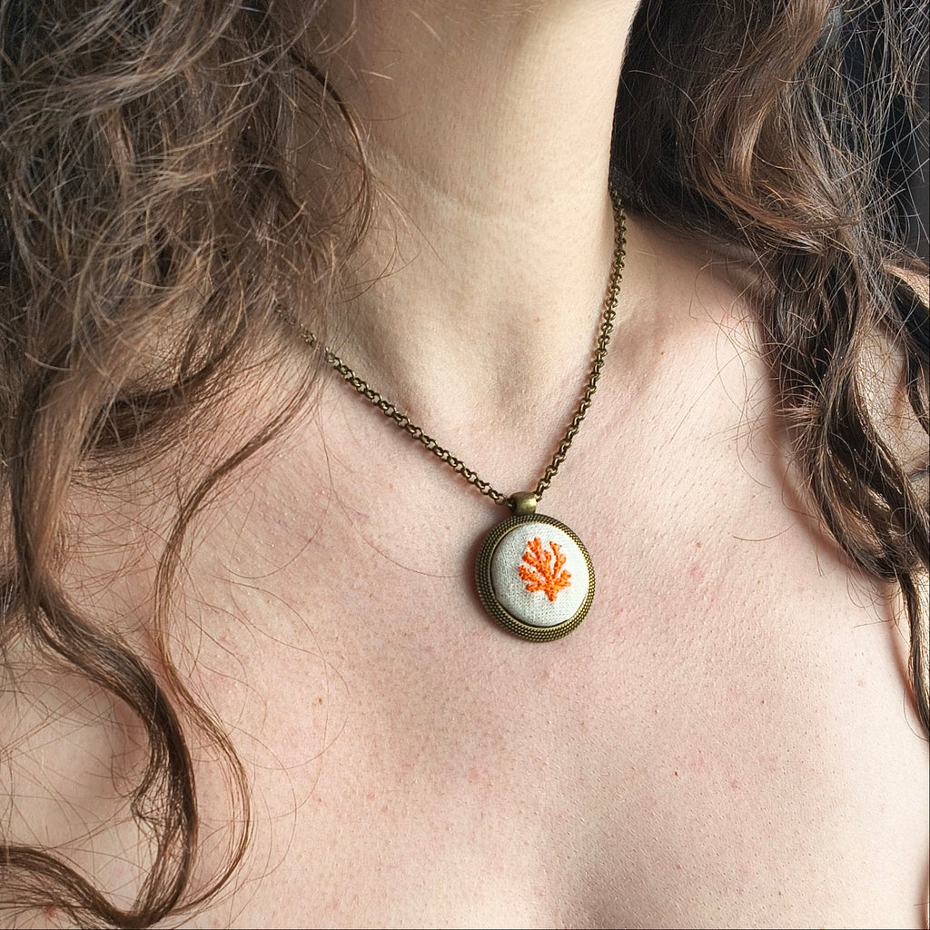 Collana artigianale Fildisogno con simbolo ricamato in tessuto, dettagli visibili sulla parte frontale della collana.