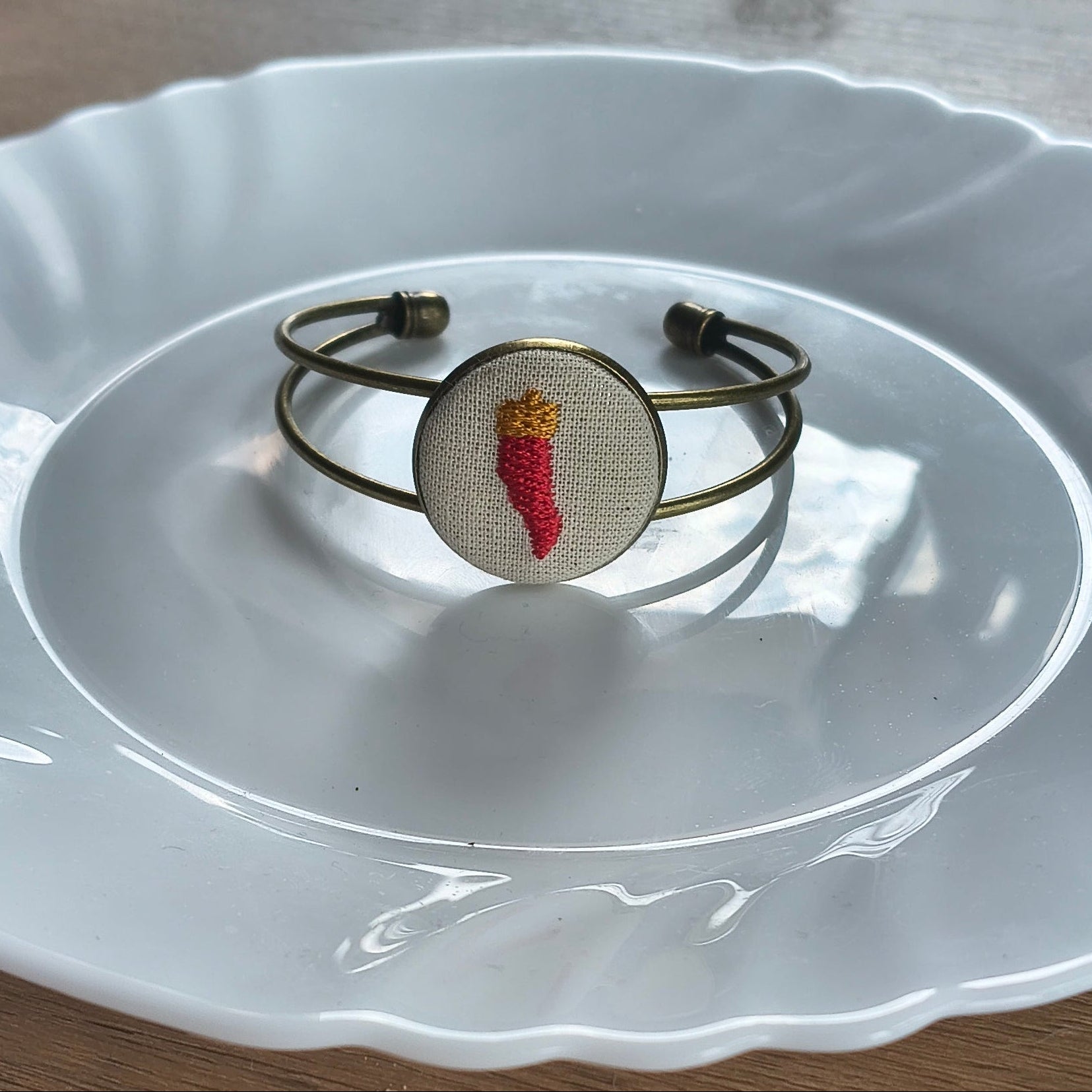 Bracciale artigianale Fildisogno con simbolo ricamato, dettagli in tessuto e finiture eleganti, visibile nell'immagine.