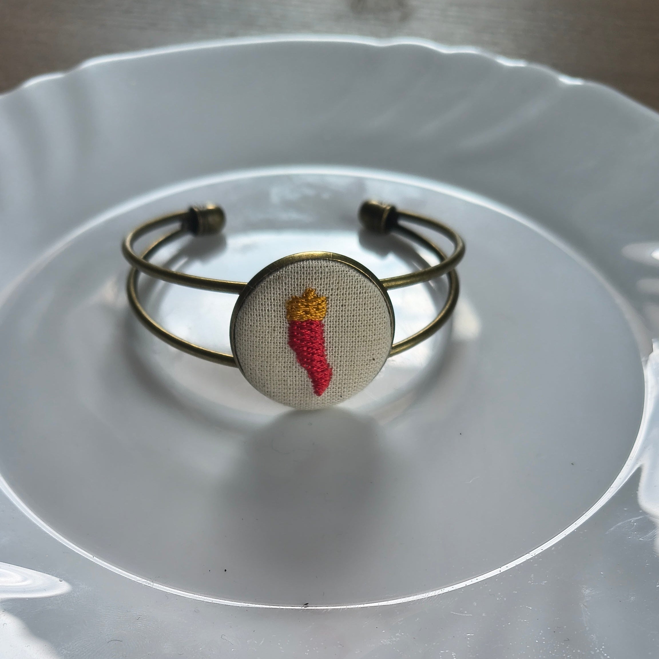 Bracciale artigianale Fildisogno con simbolo ricamato, dettaglio in tessuto e chiusura in metallo, stile unico e originale