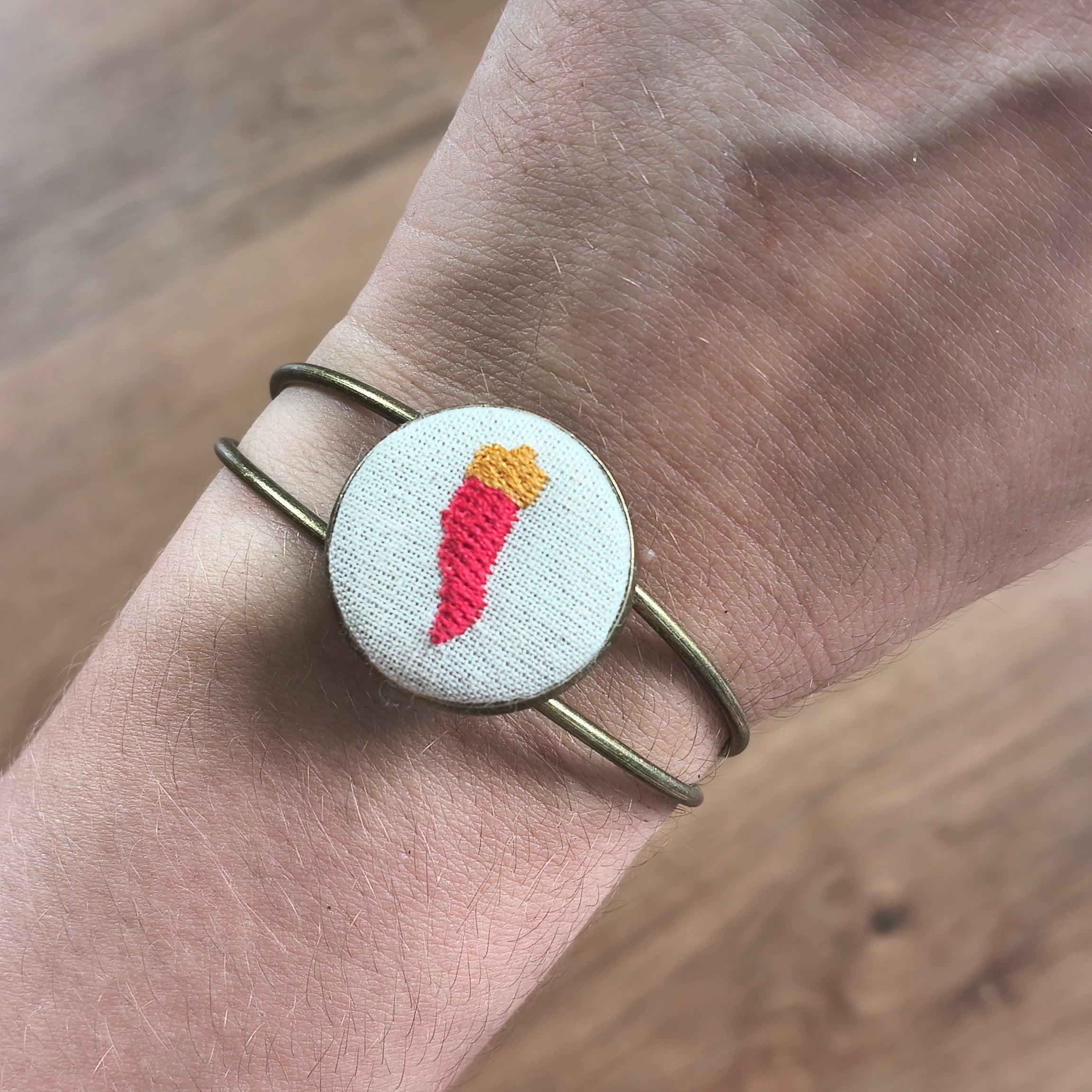 Bracciale artigianale Fildisogno con simbolo ricamato, dettaglio elegante e fatto a mano, visibile in primo piano nell'immagine.