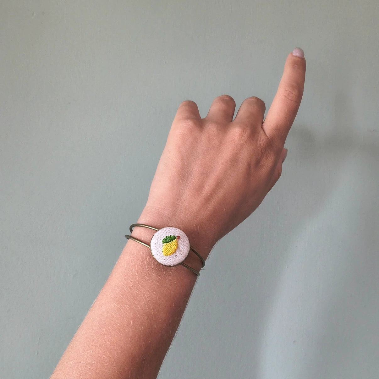 Bracciale artigianale Fildisogno con simbolo ricamato, dettagli in tessuto colorato e lavorazione fatta a mano.