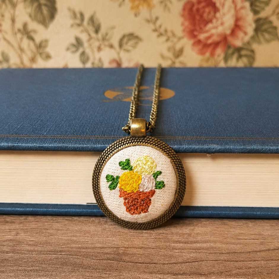 Collana con simbolo ricamato artigianale, realizzata da Fildisogno, con dettagli ricamati e design unico in metallo.