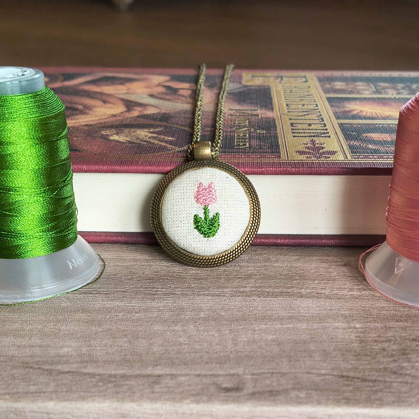 Collana artigianale Fildisogno con simbolo ricamato, dettagli raffinati e lavorazione a mano, visibile in primo piano nell'immagine.