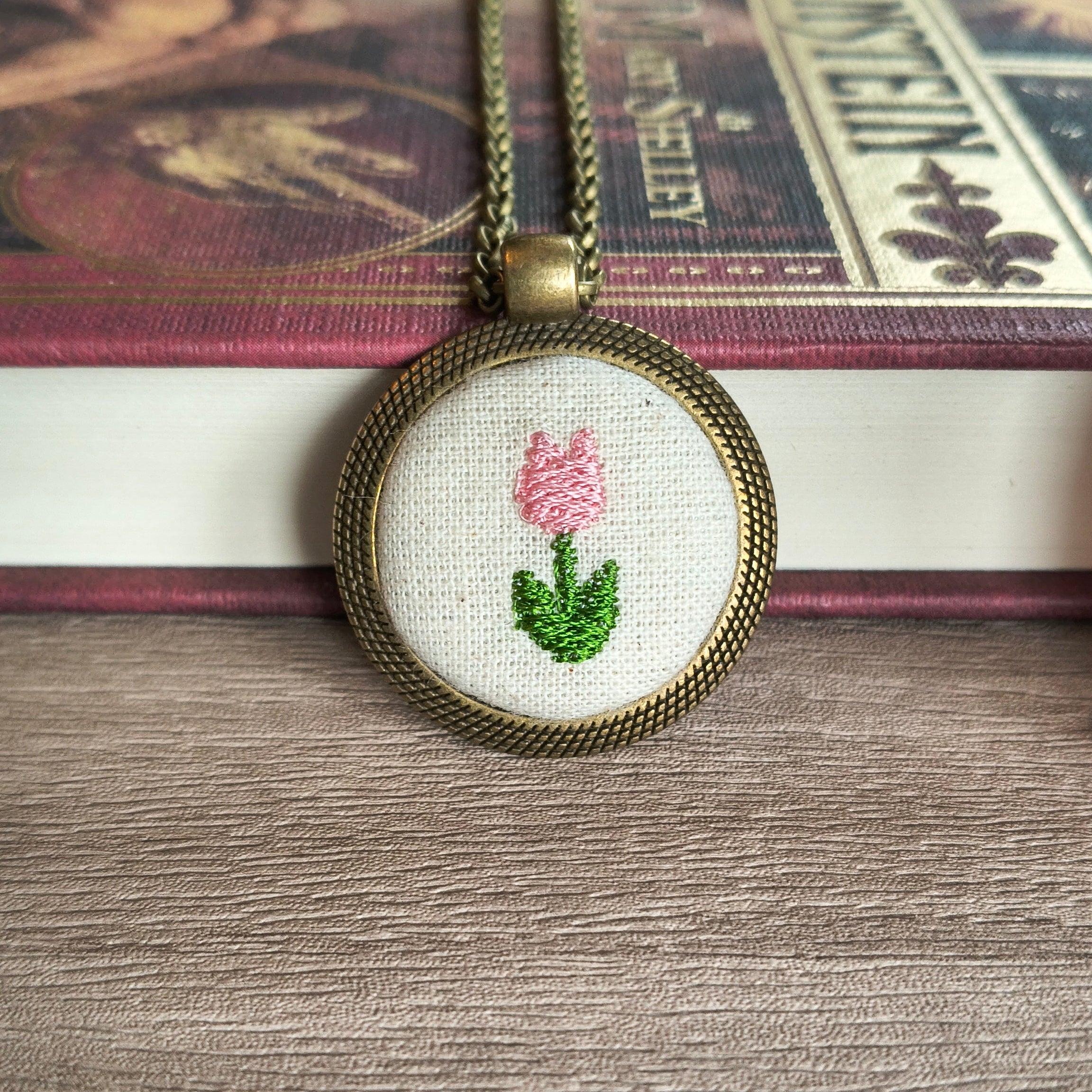 Collana artigianale con simbolo ricamato, elegante gioiello in stile Fildisogno, visibile con dettaglio di ricamo sul pendente.